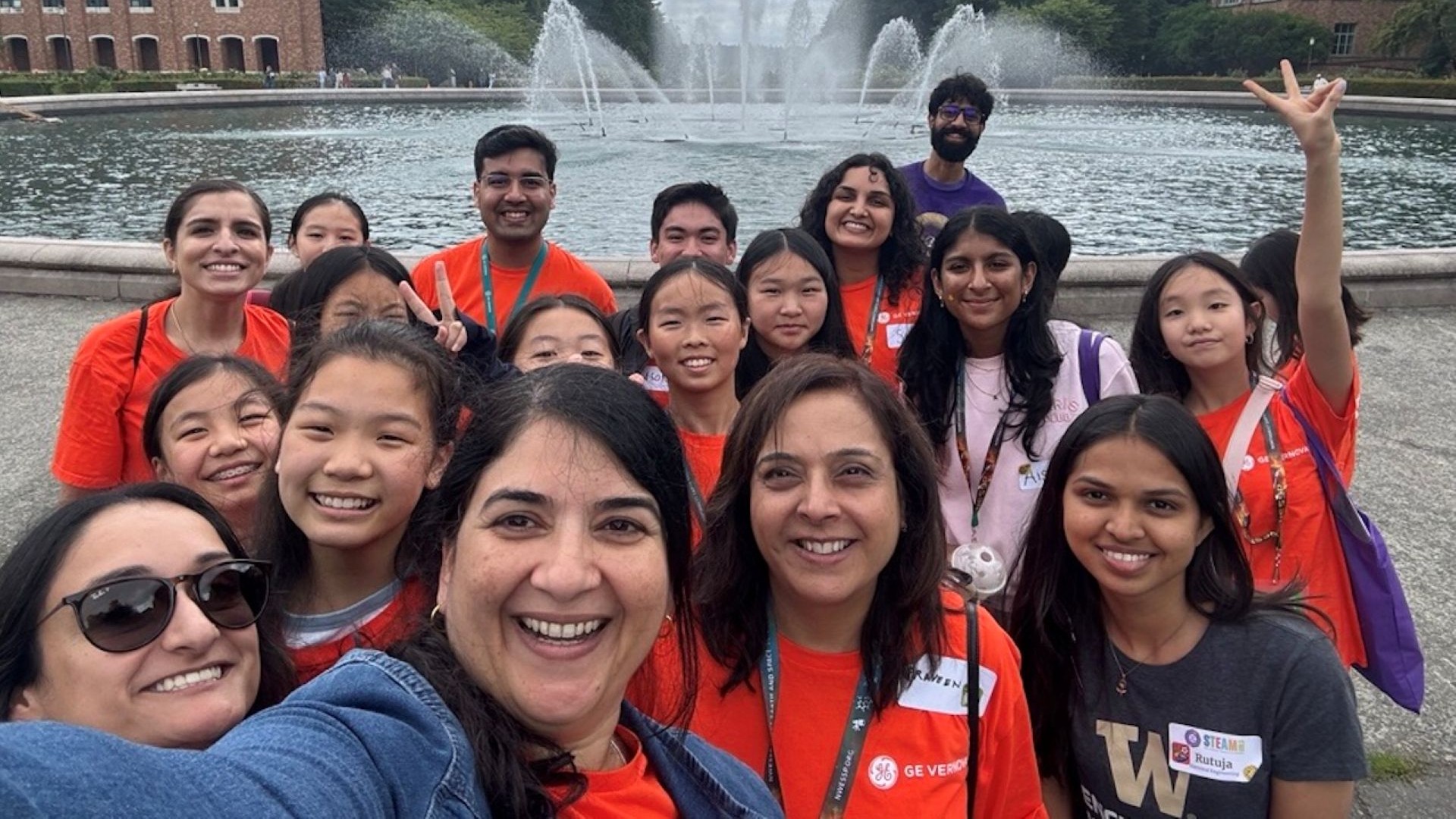 Group of women in orange taking a selfie in front of a fountain