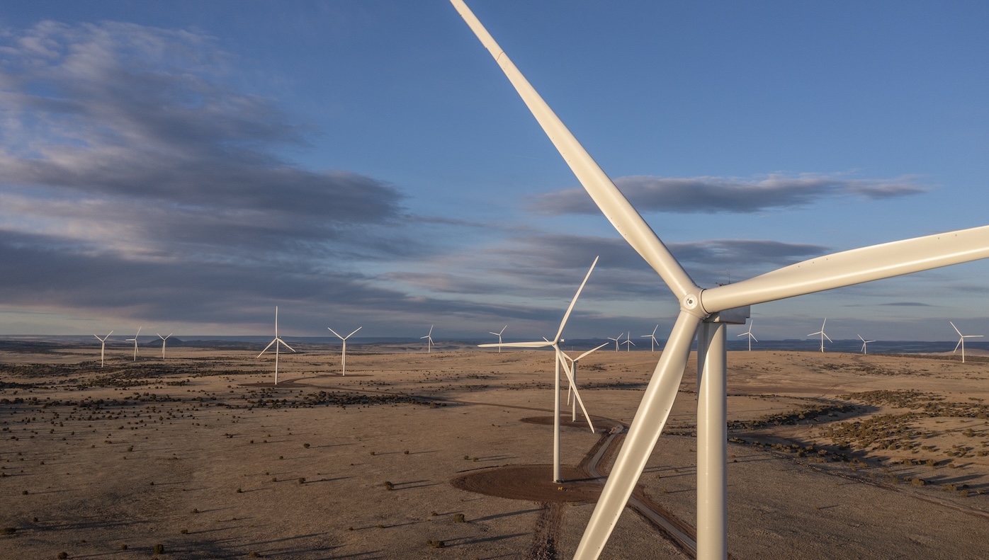 Wind turbines on a grassy plain with a blue sky in the background