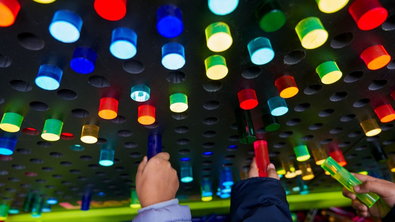 Hands reaching up to circular light rods