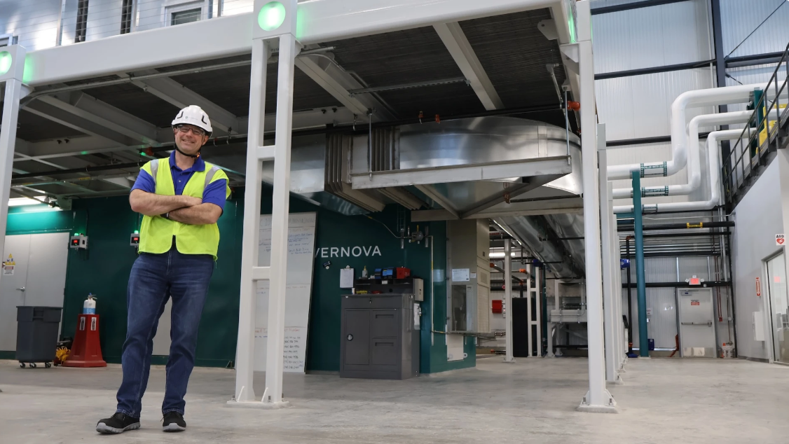 A man stands in a lab site with helmet and yellow vest