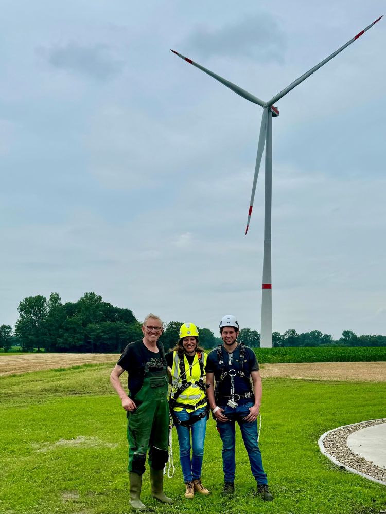 Three people standing in front of a windmill