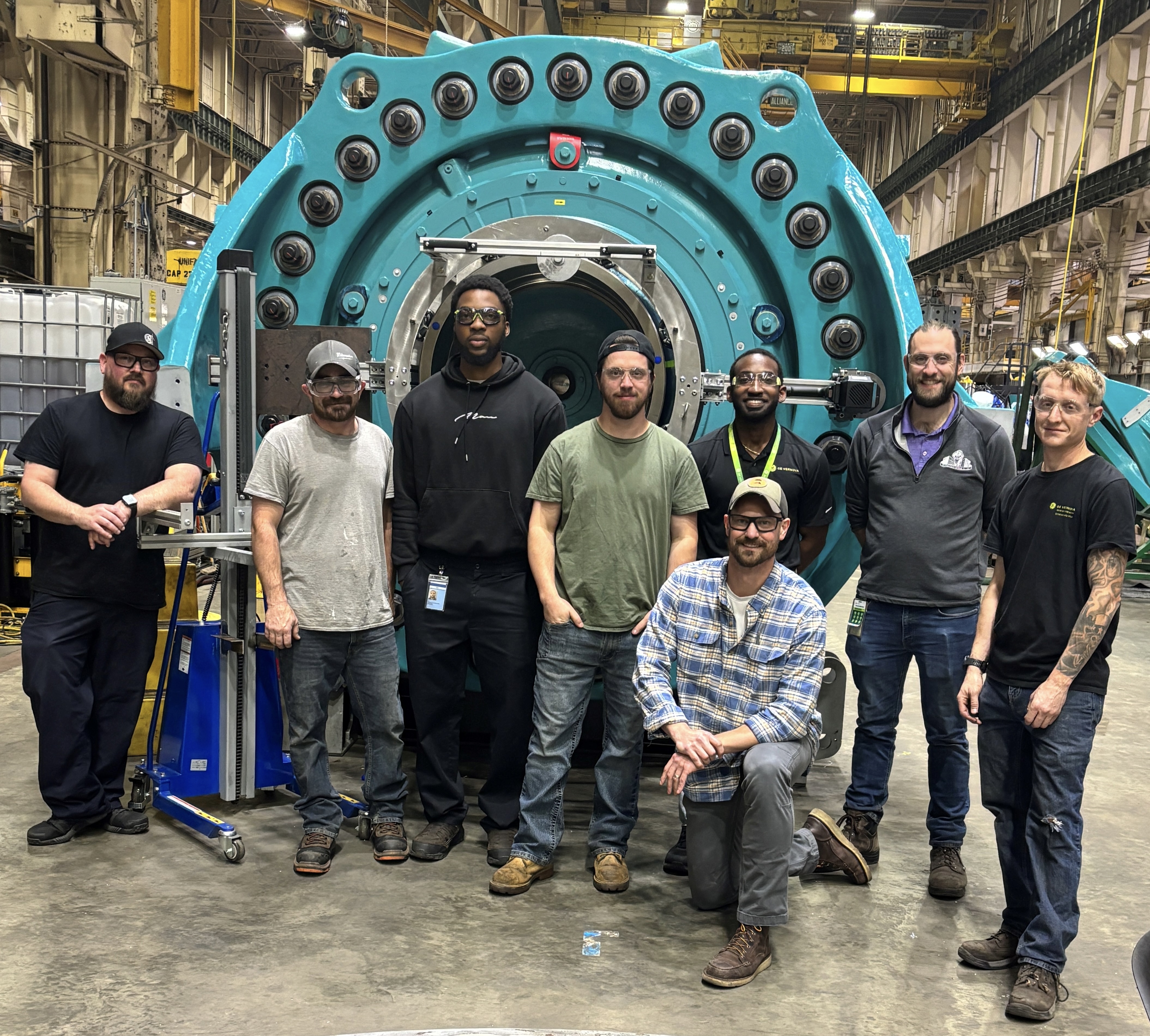 Group of men standing in front of a large piece of machinery