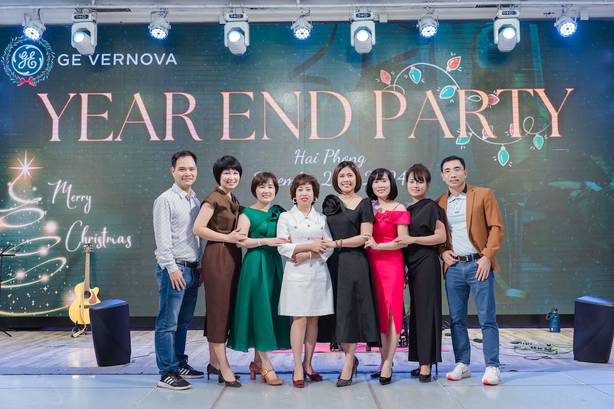 Group of people in formal wear in front of a sign that reads "Year End Party"
