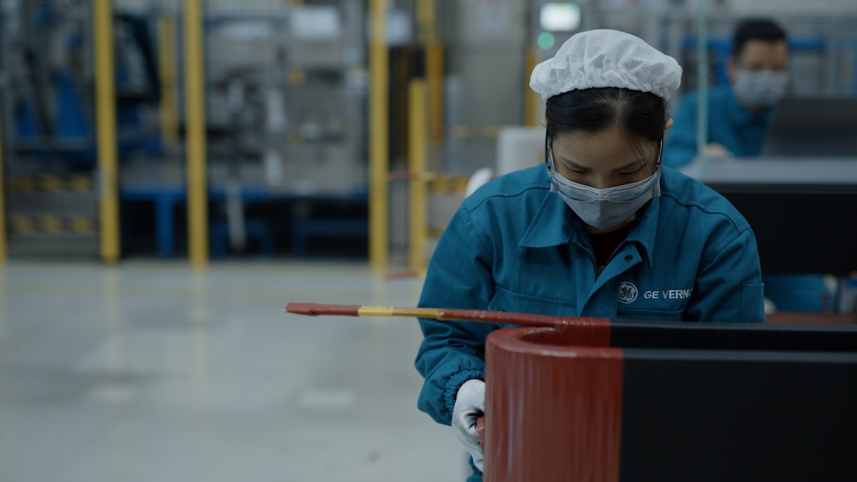 Woman in blue work gear an scrub cap doing work