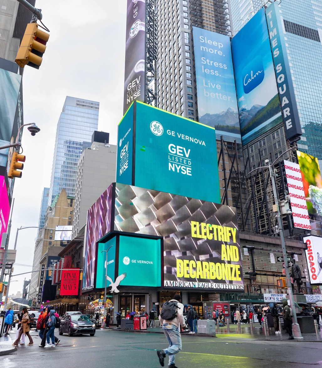 A person walking on a street with a large billboard

Description automatically generated