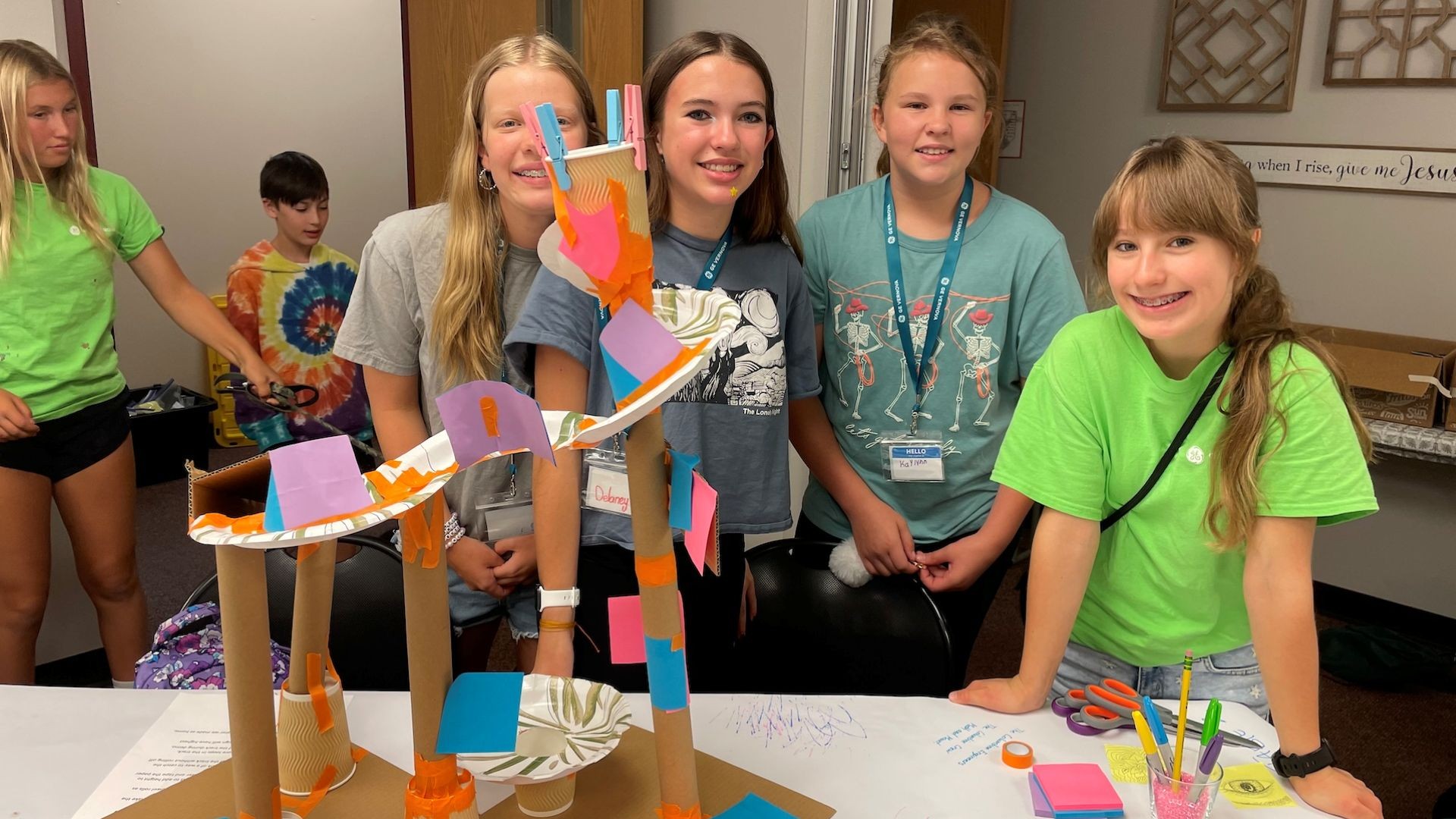 Four girls posing in front of colorful structure they built