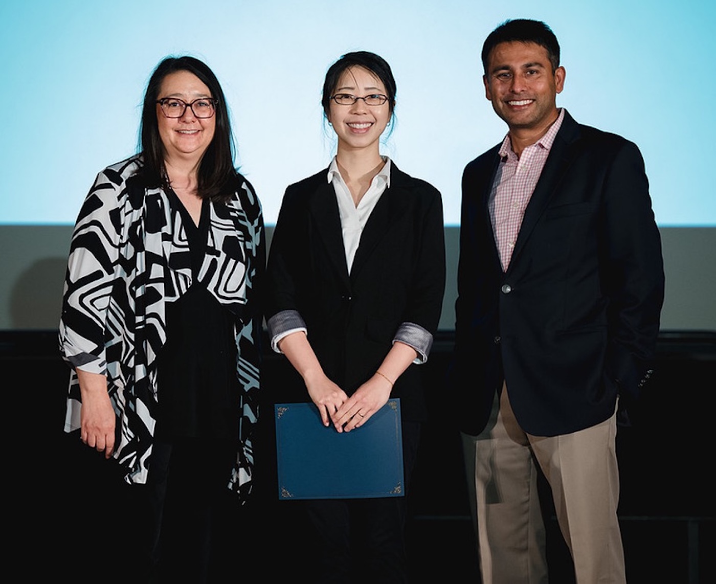 Melanie Li Sing How, an active member of GE Vernovaâs Asian Pacific Allies and Friends employee resource group, receiving the 2025 Society of Asian Scientists & Engineers (SASE) Professional Achievement Award in Pittsburgh with a male and female colleague by her side.