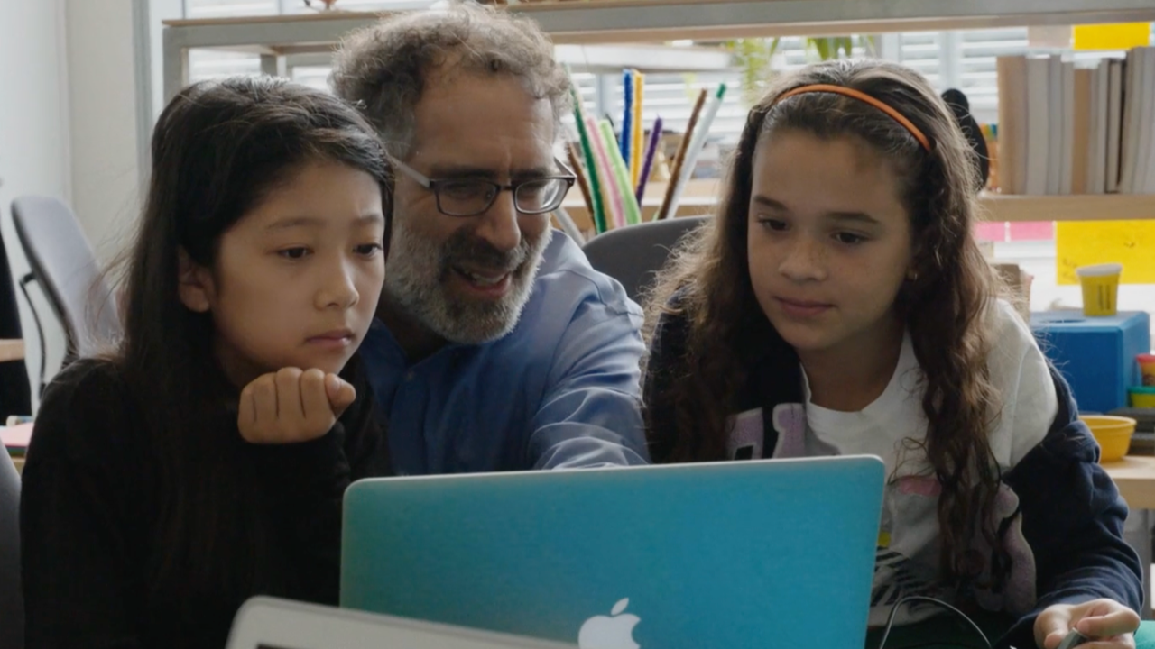Man showing two girls something on a computer
